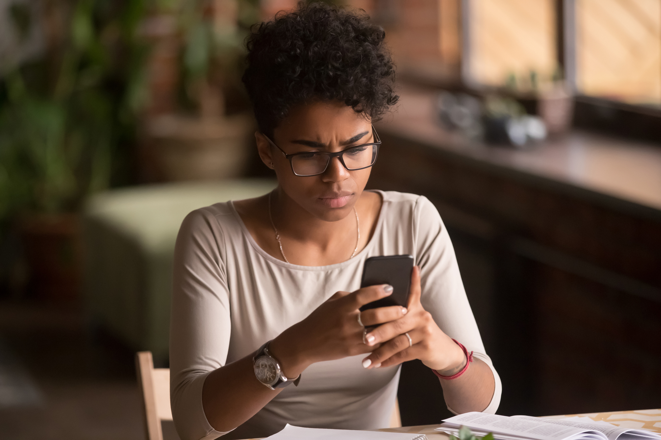 A smartly dressed woman using her mobile phone at a table