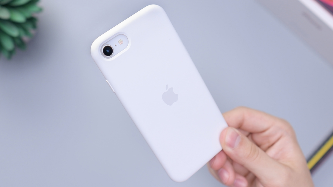 A person holding an iPhone facing backwards above a clean desk