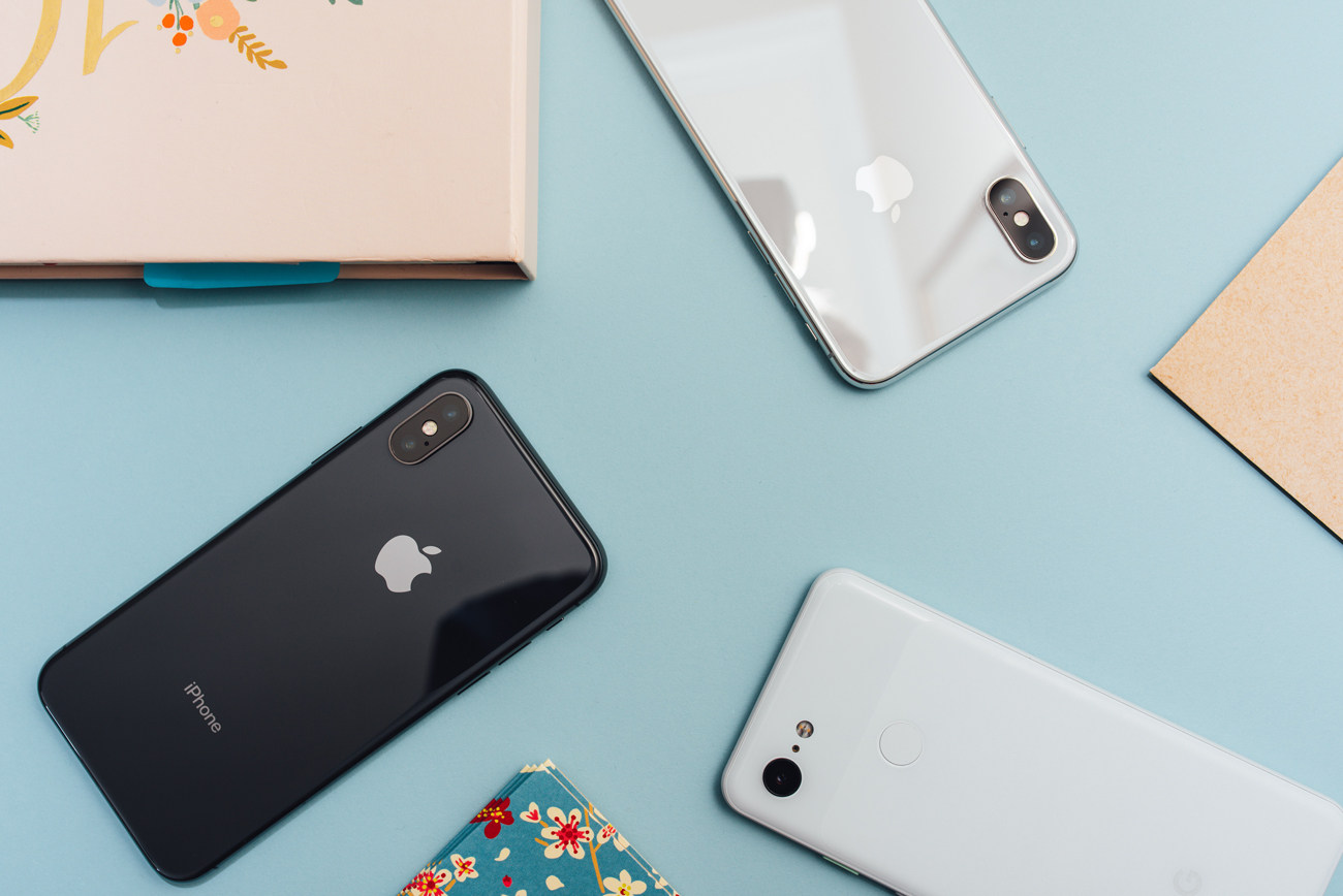 Three iPhones arranged adjacent to each other face down against a blue background